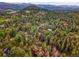 An aerial view showing homes nestled among dense trees on a hillside surrounded by mountain views at 26765 Bradley St, Conifer, CO 80433