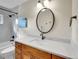 Bathroom vanity featuring wood cabinets, white countertops, oval mirror, and updated fixtures at 26765 Bradley St, Conifer, CO 80433