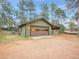 A detached two car garage with an attached covered parking area, and surrounded by beautiful pine trees at 26765 Bradley St, Conifer, CO 80433