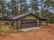 A detached two car garage with an attached covered parking area, surrounded by mature trees at 26765 Bradley St, Conifer, CO 80433