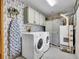 Well-organized laundry room with washer, dryer, cabinets, and stylish wallpaper at 26765 Bradley St, Conifer, CO 80433