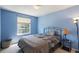 Blue bedroom with natural light, including a comfortable bed and stylish side table with lamp at 10295 Ravenswood Ln, Highlands Ranch, CO 80130