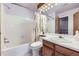 Well-lit bathroom with shower-tub combo, single sink vanity, and wood trimmed mirror at 1325 S Idalia St, Aurora, CO 80017