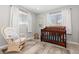 Cozy Bedroom features a crib and a rocking chair by the window at 6616 Zinnia St, Arvada, CO 80004