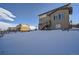 Spacious backyard with snow covering, deck and stairs leading to home at 14461 Mosaic Ave, Parker, CO 80134