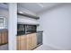 Basement wet bar featuring custom cabinets, shelving, a sink, and beverage cooler at 1821 N Grove St, Denver, CO 80204