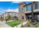 Modern townhome with a well-maintained front yard, green grass, and a contemporary design under a blue sky at 5371 E 63Rd Pl, Commerce City, CO 80022