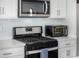 Modern kitchen featuring stainless steel appliances, including a microwave and oven, complemented by white cabinetry at 5371 E 63Rd Pl, Commerce City, CO 80022