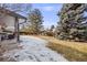 Snowy backyard with mature landscaping, a patio area, and wood fence at 6323 W Rowland Cir, Littleton, CO 80128