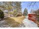 Fenced backyard with a combination of grass and snow with mature trees and red-painted deck at 6323 W Rowland Cir, Littleton, CO 80128