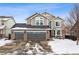 Two-story house with three-car garage, brick accents, and snow-covered lawn at 15967 Butterwort Cir, Parker, CO 80134