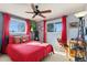 Inviting bedroom with red accents, ceiling fan, two large windows, and comfortable furnishings at 200 Bothun Rd, Berthoud, CO 80513