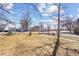 Property's charming front yard view with mature trees and a sidewalk leading to the home at 103 Sunset St # A, Longmont, CO 80501