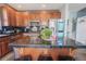 Kitchen island has wood cabinetry, black countertops and modern stainless steel appliances and a view to breakfast nook at 1586 S Goldbug Cir, Aurora, CO 80018