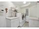 Well-equipped laundry room with front-loading machines, sink, and storage shelving at 3557 Palmer Ridge Dr, Parker, CO 80134