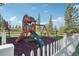 Fun outdoor playground and swing set surrounded by a white picket fence and natural landscape at 3557 Palmer Ridge Dr, Parker, CO 80134