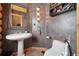 Rustic powder room features unique textured walls, pedestal sink, and charming lighting at 3557 Palmer Ridge Dr, Parker, CO 80134