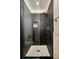 Modern bathroom featuring dark tile, glass shower doors, and gold fixtures at 40 S Dexter St, Denver, CO 80246