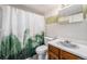Bathroom with a floral green and gold shower curtain and light wood vanity at 6235 W Floyd Ave, Denver, CO 80227