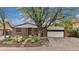 Charming brick home featuring a two-car garage, landscaped front yard, mature tree, and concrete driveway at 6235 W Floyd Ave, Denver, CO 80227