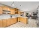 Functional kitchen featuring light wood cabinets, breakfast bar, tile flooring and a view into the living room at 6235 W Floyd Ave, Denver, CO 80227
