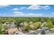 Bright aerial view of homes in a tree-filled neighborhood under a blue, partly cloudy sky at 6235 W Floyd Ave, Denver, CO 80227