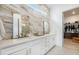 Elegant bathroom features double vanity, luxurious marble wall and tile flooring with access to walk-in closet at 7202 Canyonpoint Rd, Castle Pines, CO 80108