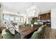 Bright dining room open to living room, features a large wood table, green chairs, and modern chandelier at 7202 Canyonpoint Rd, Castle Pines, CO 80108