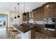 Modern kitchen featuring dark wood cabinets, stainless steel appliances, a center island, and designer pendant lights at 7202 Canyonpoint Rd, Castle Pines, CO 80108
