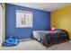 Cozy bedroom painted in yellow and blue with a window and a comfy beanbag chair at 18108 E 52Nd Ave, Denver, CO 80249