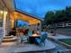 Cozy outdoor patio at dusk featuring a fire pit, stylish chairs, a built-in grill, and ambient string lights for evening relaxation at 3902 Eagle Tail Ln, Castle Rock, CO 80104
