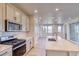 Bright, open kitchen featuring white cabinetry, stainless steel appliances, and a center island with quartz countertops at 8635 Hotchkiss St, Littleton, CO 80125