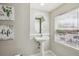 Cozy powder room with pedestal sink, oval mirror, and natural light from the window at 9300 E Florida Ave # 1107, Denver, CO 80247