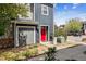 Townhome featuring a gray garage door and a bright red front door, framed by green landscaping at 9300 E Florida Ave # 1107, Denver, CO 80247