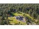 Aerial view of a luxury home nestled among mature trees with a circular driveway and fenced yard at 230 S Big Meadow Trl, Franktown, CO 80116