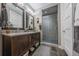 Modern bathroom features double sink vanity with granite countertop, framed mirrors, tile floors, and glass enclosed shower at 230 S Big Meadow Trl, Franktown, CO 80116
