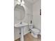 Bathroom featuring round mirror, pedestal sink, and white toilet at 5341 N Rhyolite Way, Parker, CO 80134