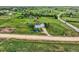 Aerial view of a light blue home with large yard, fences, trees, and road in the background at 8370 Midsummer Ln, Elizabeth, CO 80107