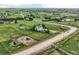 Aerial view of light blue house with solar panels in large green lot with sheds and fences in a rural area at 8370 Midsummer Ln, Elizabeth, CO 80107