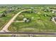 Wide aerial shot of light blue house with solar panels surrounded by green fields, fences, and a road at 8370 Midsummer Ln, Elizabeth, CO 80107
