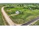 Wide aerial view of a light blue house with solar panels on a large green lot surrounded by fences at 8370 Midsummer Ln, Elizabeth, CO 80107