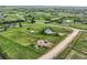 Aerial view of light blue house with solar panels surrounded by a large green yard, sheds, and fence at 8370 Midsummer Ln, Elizabeth, CO 80107