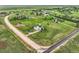 Aerial view of light blue house with solar panels on large green lot with sheds and fences in a rural area at 8370 Midsummer Ln, Elizabeth, CO 80107