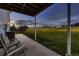 Covered backyard patio area with chairs, offering a shady spot overlooking the expansive grassy yard at 8370 Midsummer Ln, Elizabeth, CO 80107