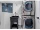 Laundry room featuring a stacked washer and dryer, utility sink, and modern tile backsplash and flooring at 2320 S Valley Hwy, Denver, CO 80222