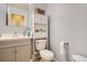 Bright bathroom featuring a white toilet, sink with cabinet, and additional shelving for storage at 676 Hedgerow Way, Brighton, CO 80601