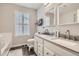 Bathroom featuring double sinks with modern fixtures, vanity cabinets, and a large window providing natural light at 676 Hedgerow Way, Brighton, CO 80601