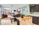 Open-concept dining area adjacent to kitchen and living space featuring a long wooden table and bench seating at 676 Hedgerow Way, Brighton, CO 80601