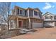Charming two-story home with stone accents, a red front door, a brick driveway, and a well-maintained lawn at 26167 E Byers Pl, Aurora, CO 80018