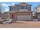 Stunning two-story home with a stone facade, a brick driveway, a red front door, and an attached two-car garage at 26167 E Byers Pl, Aurora, CO 80018